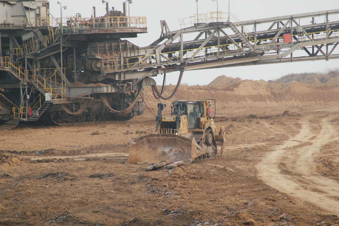Bulldozer bekerja di dekat mesin tambang berukuran besar di area pertambangan terbuka