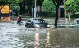 Mobil-mobil melintasi jalan yang tergenang banjir saat hujan badai