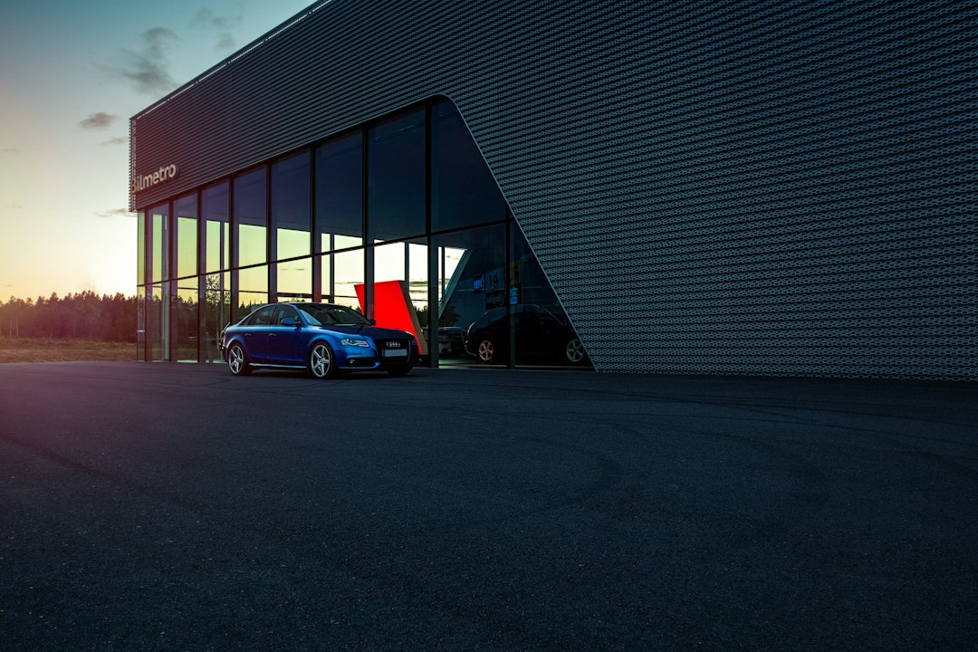 Sedan biru terparkir di depan gedung showroom mobil